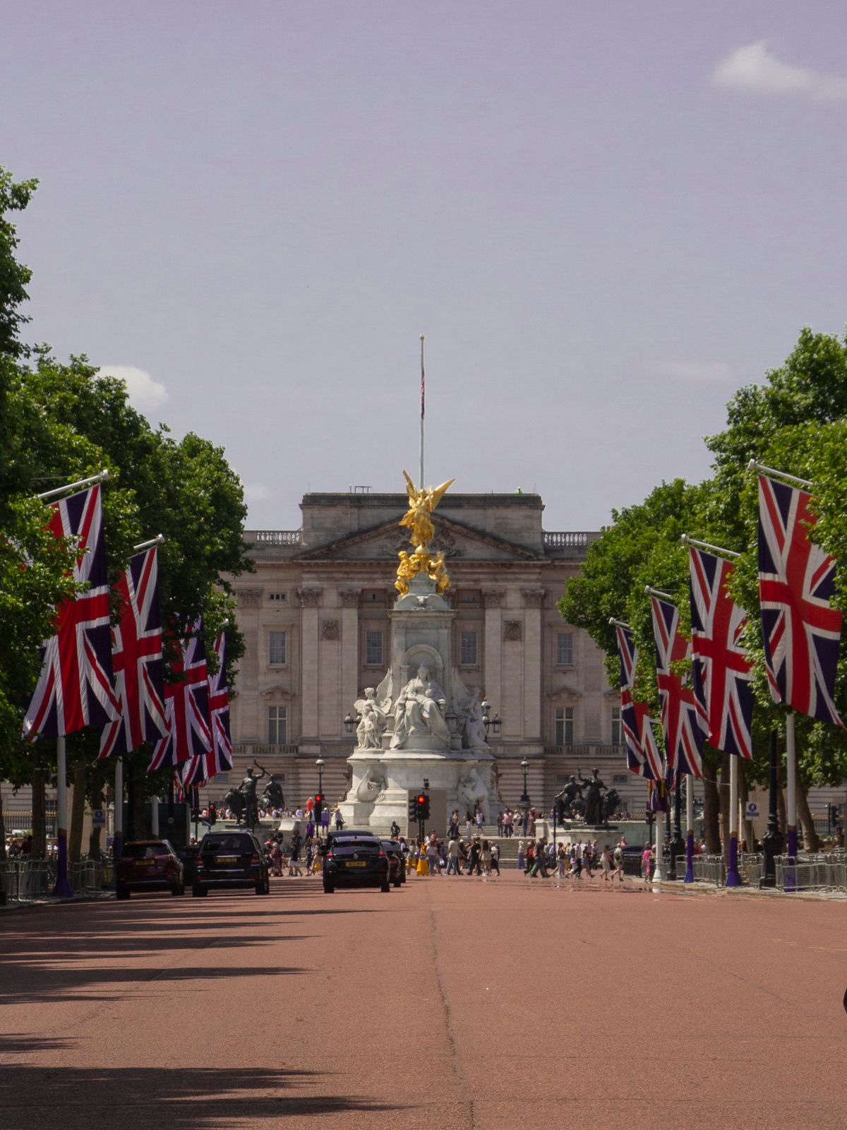 View of Buckingham Palace in London with the Union Jack flags lining the street.